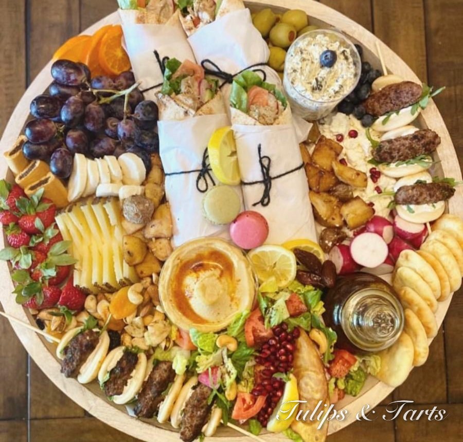 Round halal charcuterie board with wraps, kababs, hummus, fruit and cheese